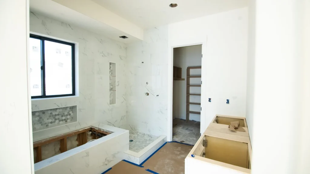A bathroom under finishing work, tiling in progress.