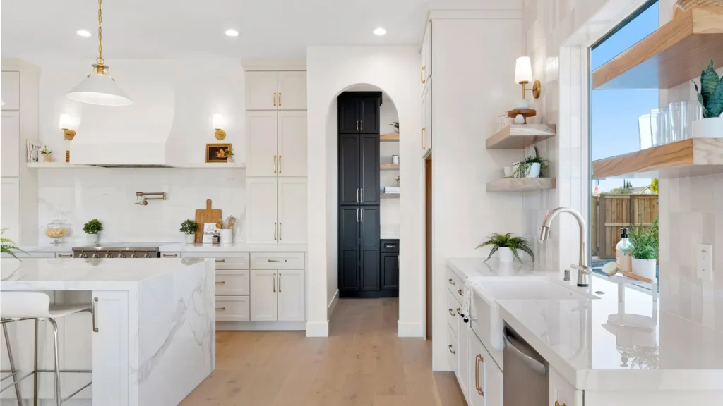 The kitchen, with a stone island, brass fittings and an arched pantry doorway.