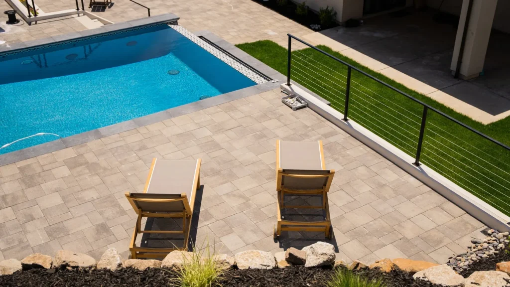 The paved pool terrace, loungers set along the water.